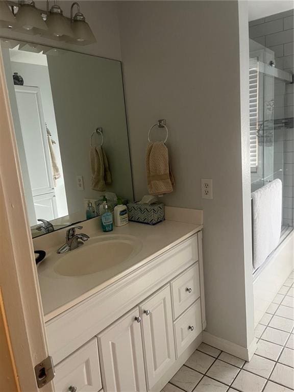 full bathroom featuring baseboards, vanity, a shower with shower door, and tile patterned floors