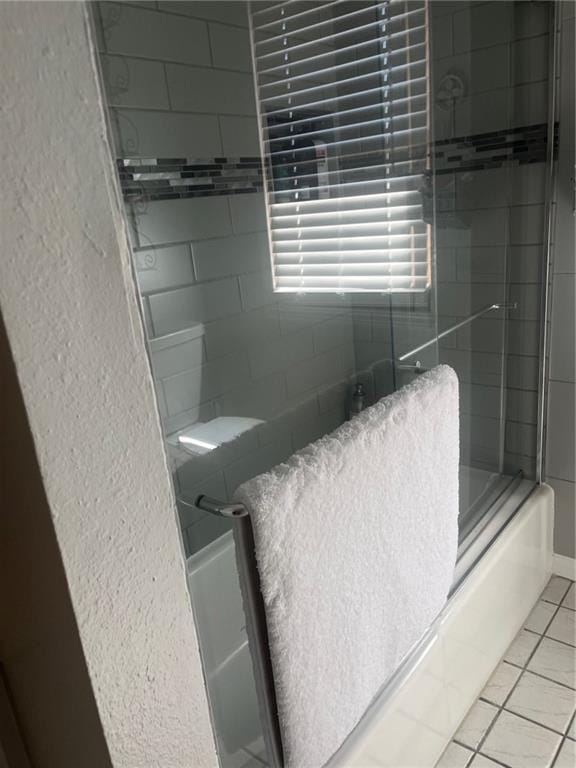 full bath featuring bath / shower combo with glass door and tile patterned floors