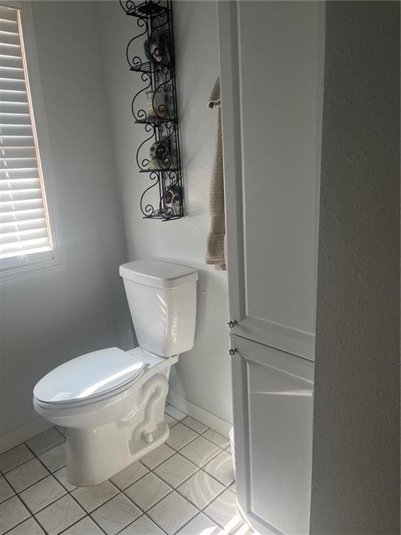 bathroom with toilet, tile patterned flooring, and baseboards