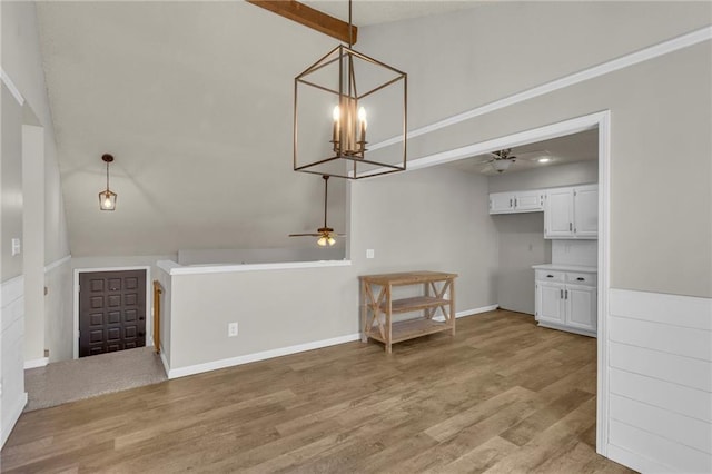 unfurnished dining area featuring lofted ceiling with beams, light wood-type flooring, baseboards, and ceiling fan with notable chandelier