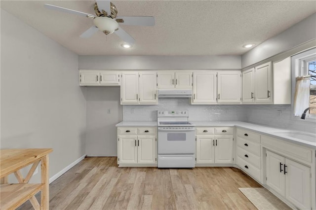 kitchen with white electric range, under cabinet range hood, light countertops, and a sink