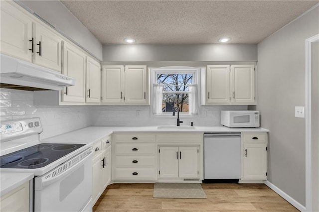 kitchen with under cabinet range hood, light wood-type flooring, white cabinets, white appliances, and a sink