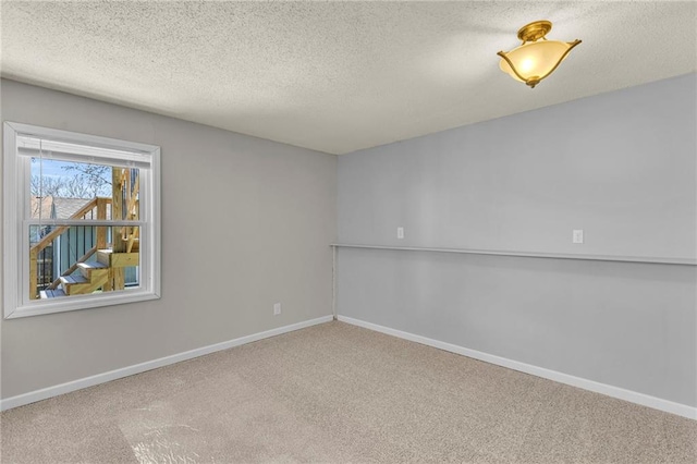 unfurnished room with carpet flooring, baseboards, and a textured ceiling