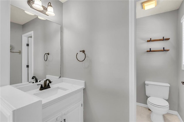 bathroom with baseboards, toilet, vanity, and tile patterned flooring