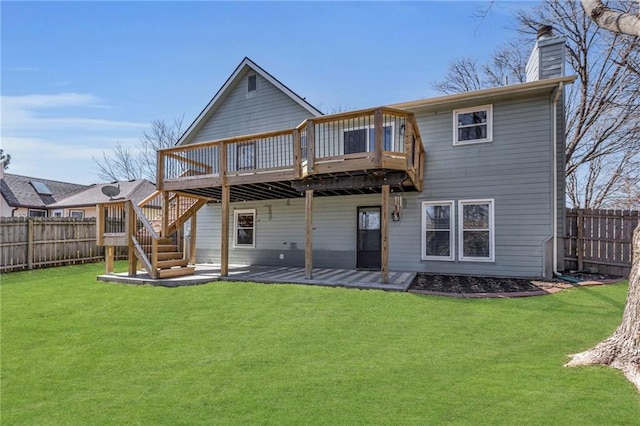 back of house with a yard, a chimney, a wooden deck, and a fenced backyard