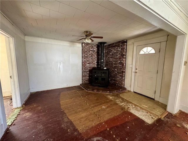 unfurnished living room featuring a wood stove and ceiling fan