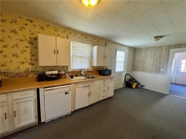 kitchen with black microwave, a sink, light countertops, dishwasher, and wallpapered walls