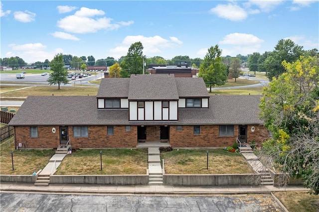 view of front of home featuring brick siding, a shingled roof, and a front yard