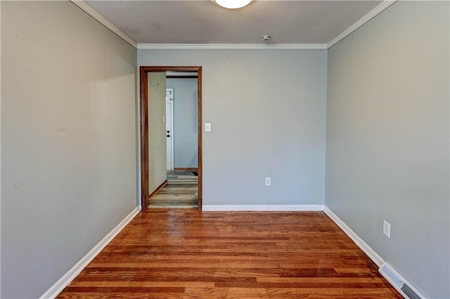 spare room featuring visible vents, crown molding, baseboards, and wood finished floors