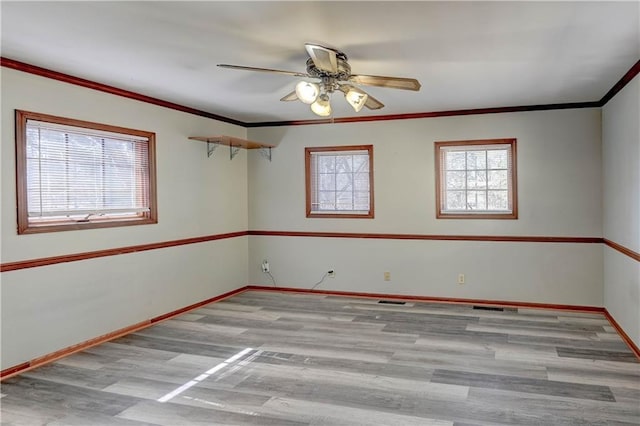 empty room featuring visible vents, baseboards, ceiling fan, wood finished floors, and crown molding