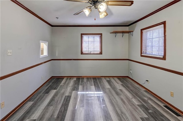 empty room featuring ornamental molding, visible vents, baseboards, and wood finished floors