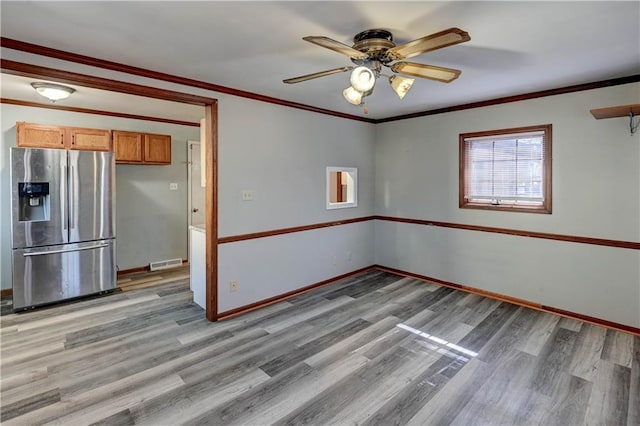 empty room featuring visible vents, crown molding, and light wood-style flooring