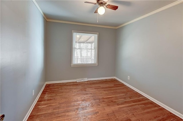 spare room featuring a ceiling fan, crown molding, baseboards, and wood finished floors