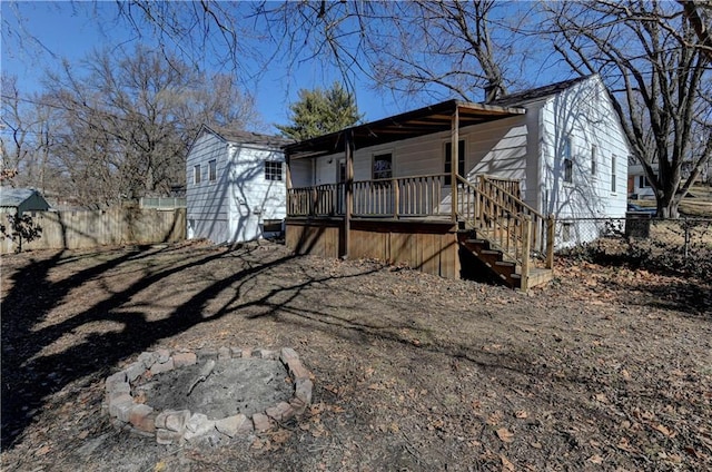 view of side of property featuring covered porch, fence, a fire pit, and stairs