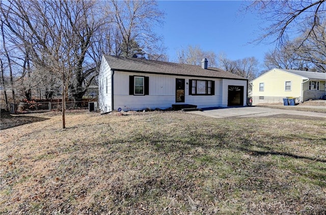 view of front of home featuring driveway, a chimney, central AC unit, and a front lawn