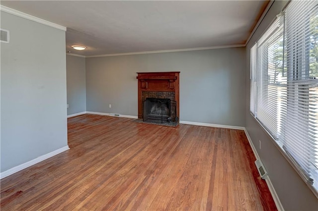 unfurnished living room featuring a fireplace with flush hearth, baseboards, wood finished floors, and crown molding