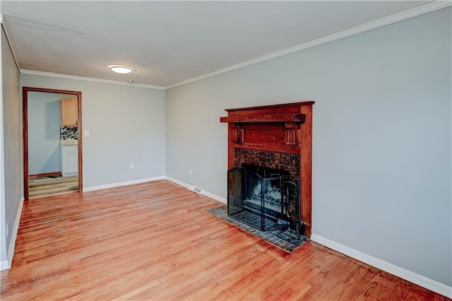 unfurnished living room featuring a fireplace with flush hearth, crown molding, light wood-style flooring, and baseboards