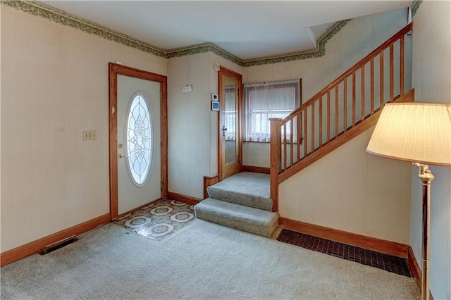 carpeted entryway featuring visible vents, stairway, and baseboards