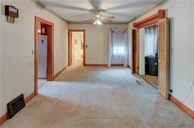 carpeted spare room featuring baseboards, visible vents, and ornamental molding