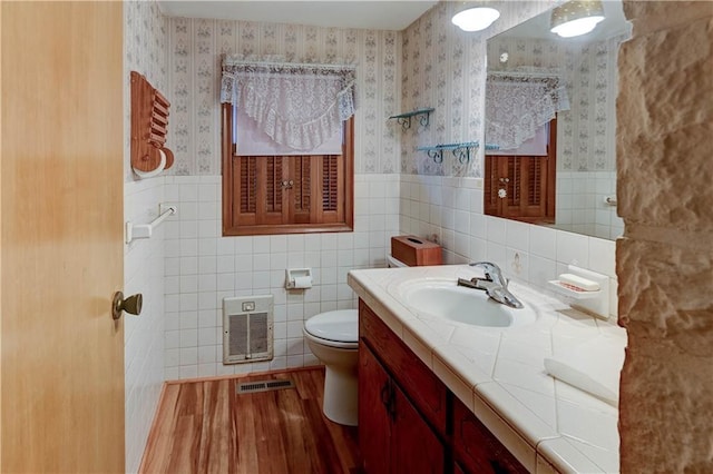 half bathroom featuring toilet, wallpapered walls, visible vents, and wainscoting