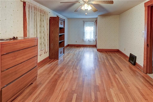 unfurnished bedroom with wallpapered walls, light wood-style flooring, baseboards, and ceiling fan