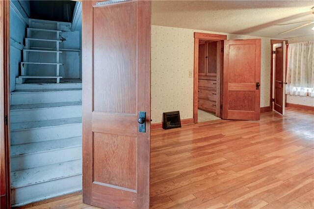 interior space with light wood-style floors, ceiling fan, baseboards, and wallpapered walls