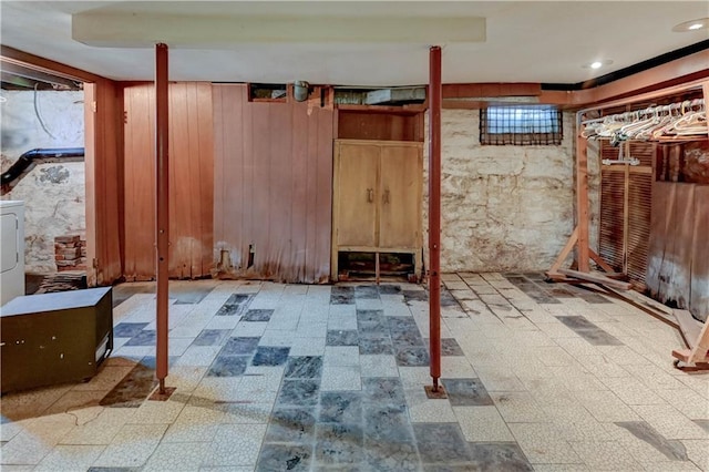 unfinished basement with wooden walls and tile patterned floors