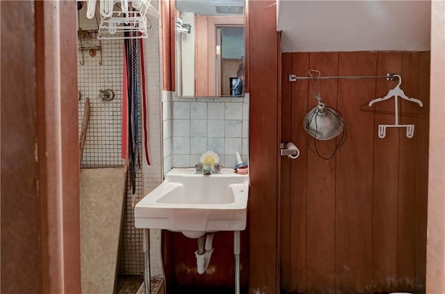 bathroom with tasteful backsplash, a sink, and tile walls