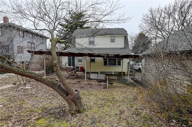 rear view of property with a shingled roof and a patio