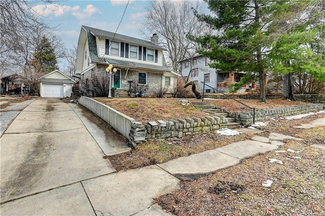 dutch colonial with an outdoor structure, a detached garage, concrete driveway, stone siding, and a chimney