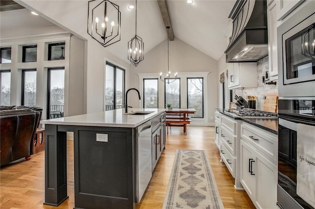 kitchen with a sink, a chandelier, stainless steel appliances, beamed ceiling, and custom exhaust hood
