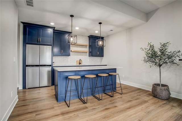 kitchen with blue cabinets, light countertops, baseboards, freestanding refrigerator, and light wood-style floors