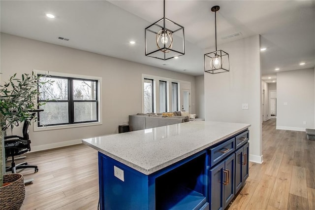 kitchen featuring pendant lighting, baseboards, open floor plan, blue cabinets, and light wood finished floors