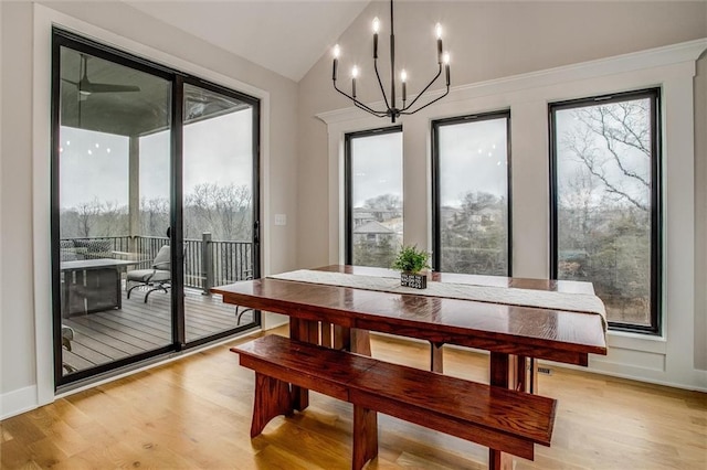dining space featuring light wood-style floors, baseboards, a notable chandelier, and vaulted ceiling