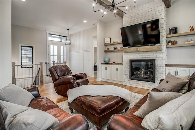 living room with an inviting chandelier, a large fireplace, light wood-style flooring, and a wainscoted wall