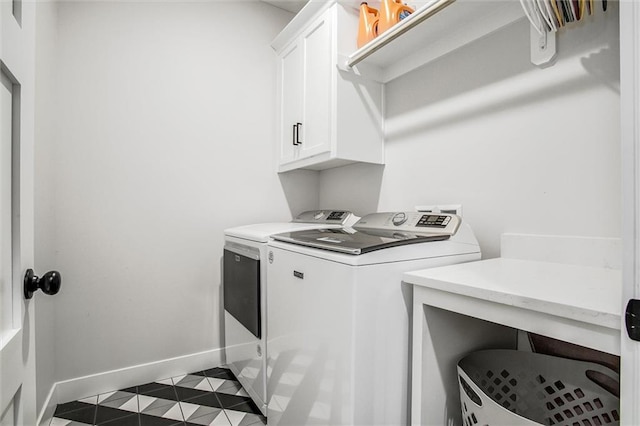 laundry area featuring dark tile patterned flooring, baseboards, cabinet space, and washer and clothes dryer