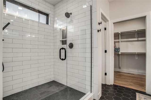 full bath featuring a walk in closet, tile patterned floors, and a shower stall