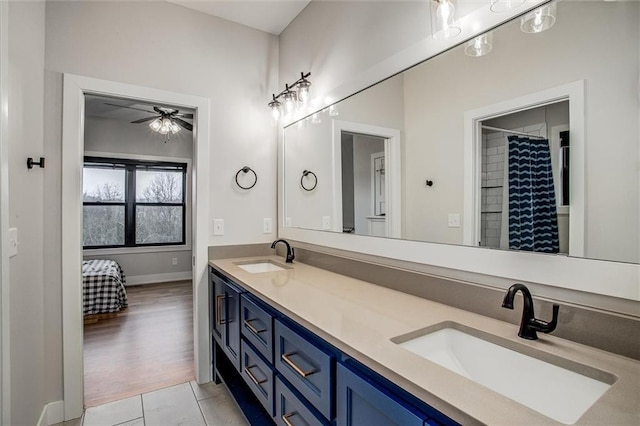 bathroom with double vanity, a sink, baseboards, and ceiling fan