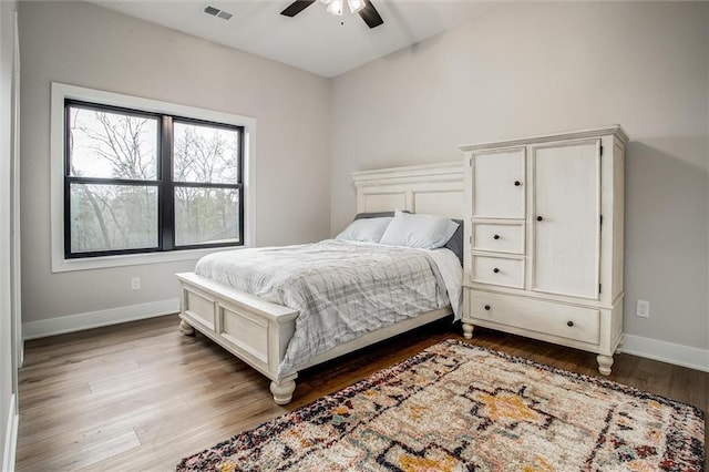 bedroom with visible vents, a ceiling fan, baseboards, and wood finished floors