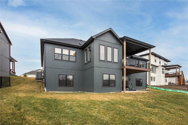 rear view of property featuring a lawn, central AC unit, and a balcony