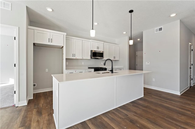 10613 N Jefferson St, Kansas City, MO 64155 - kitchen with stainless steel microwave, a center island with sink, light countertops, dark wood finished floors, and white cabinets