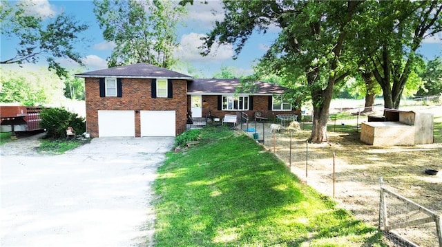 tri-level home featuring brick siding, a front yard, fence, a garage, and driveway