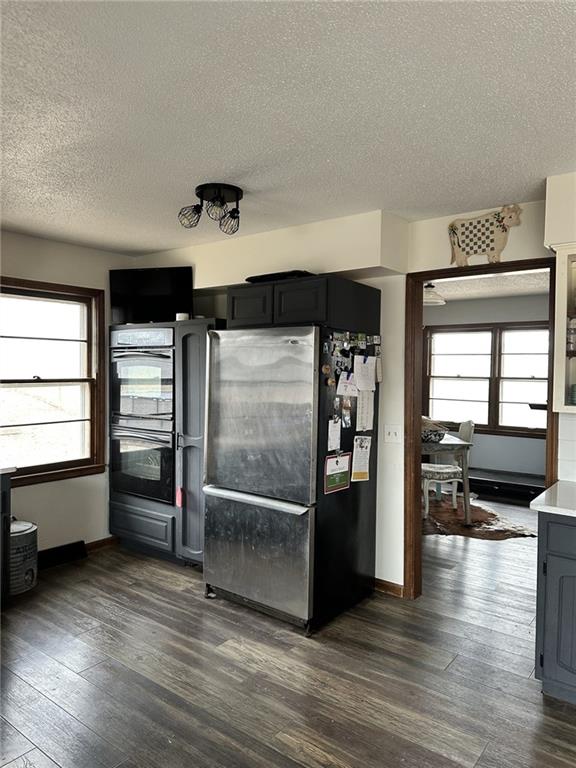 kitchen with a wealth of natural light, dark wood-type flooring, freestanding refrigerator, and dobule oven black