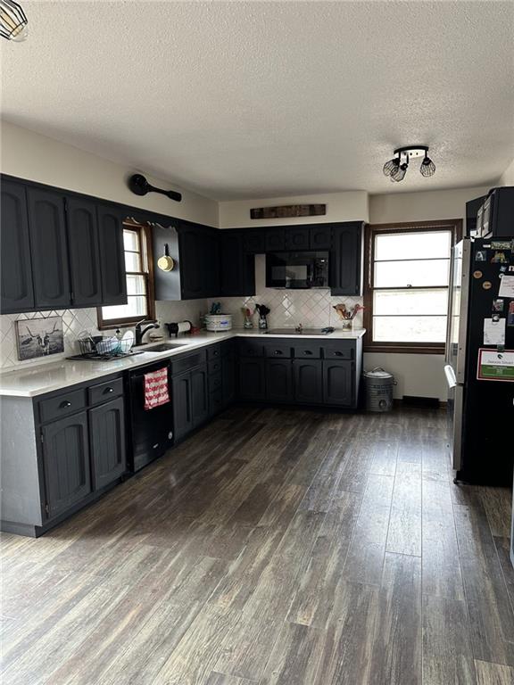 kitchen with dishwashing machine, light countertops, a sink, and freestanding refrigerator