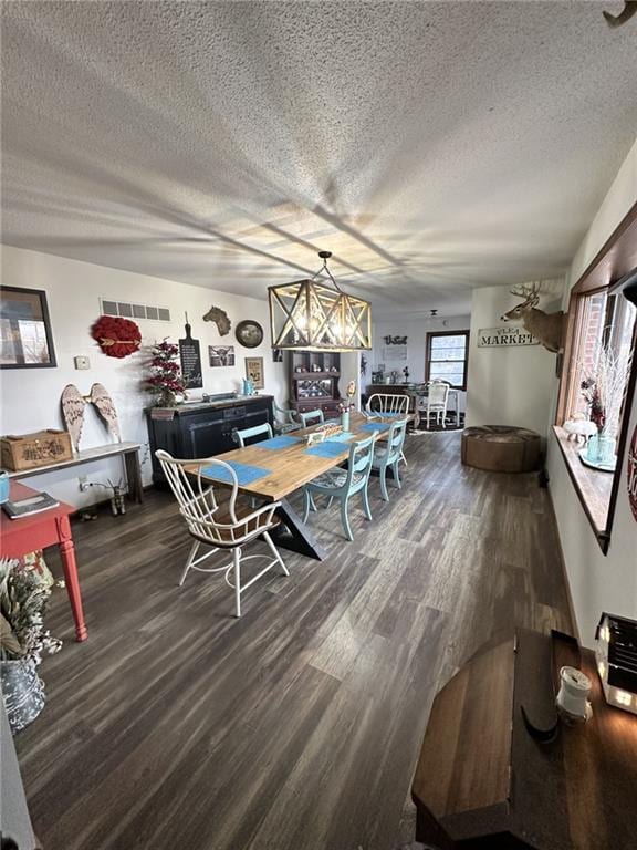 dining space featuring visible vents, a textured ceiling, and wood finished floors