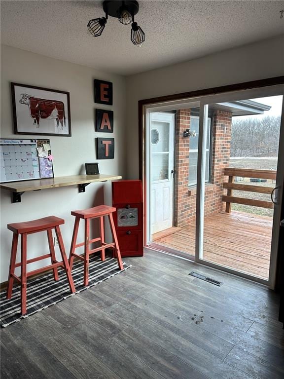 doorway featuring a textured ceiling, visible vents, and wood finished floors