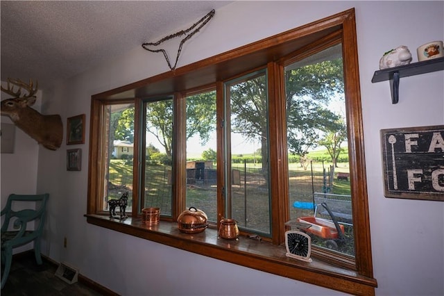 doorway to outside with a textured ceiling, visible vents, and baseboards