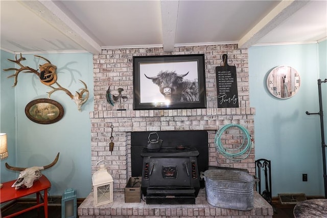 details featuring a wood stove, visible vents, ornamental molding, and beamed ceiling