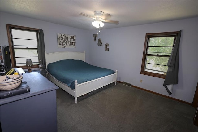 unfurnished bedroom with visible vents, dark carpet, baseboards, and ceiling fan