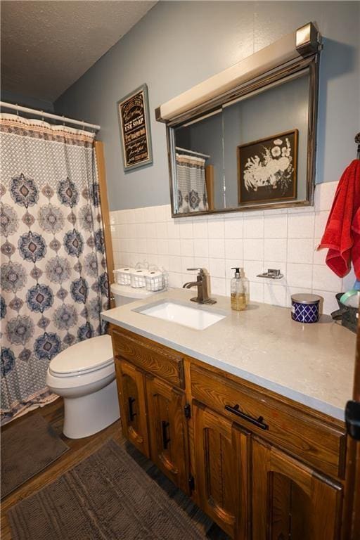 full bath with toilet, curtained shower, a textured ceiling, vanity, and tile walls